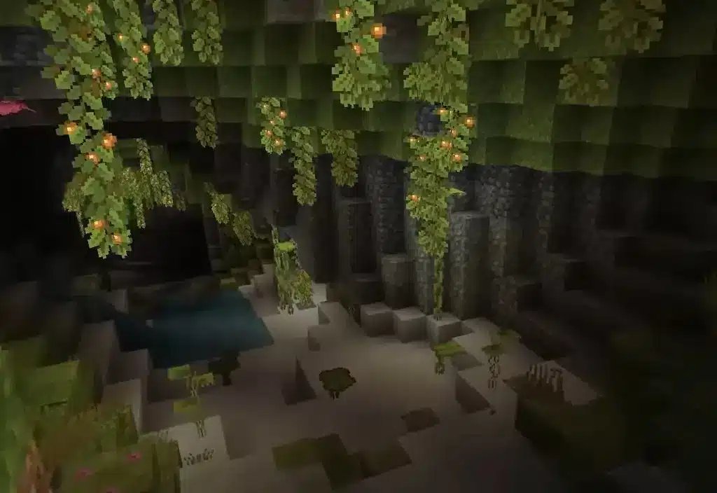 Pohled na biom Lush Caves v Minecraftu, ve kterém jsou vidět visící svítící bobule a zeleň.
