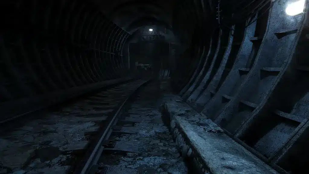 Temný, atmosférický pohled na opuštěný tunel metra se zrezivělými kovovými podpěrami a tlumeným osvětlením.